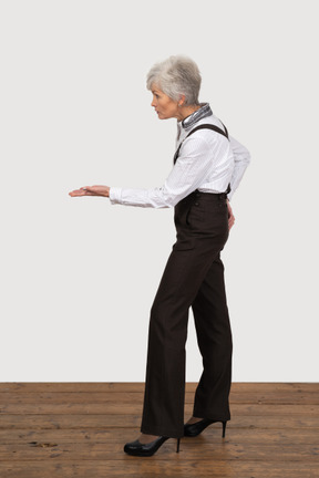 Side view of an old lady in office clothing outstretching her hand