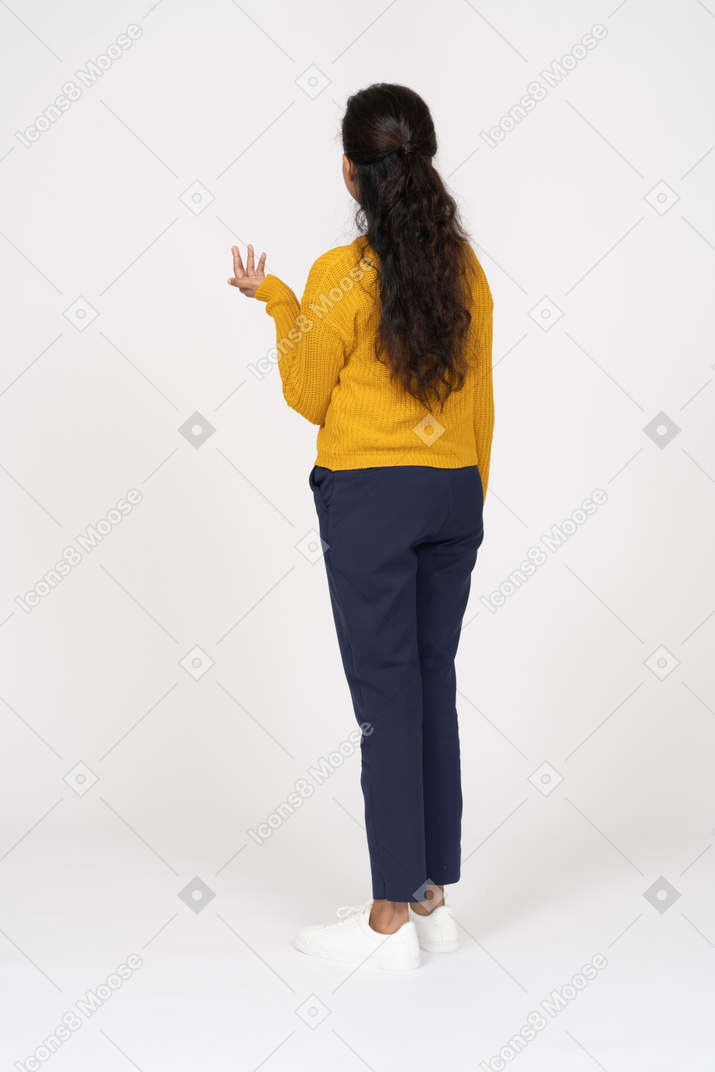 一个穿着休闲服的女孩举起手站立的后视图