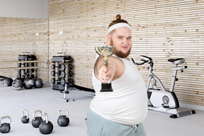 A man holding a trophy in a gym