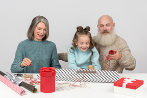 Grandparents and granddaughter wrapping christmas gifts