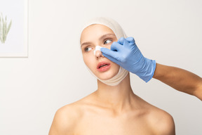 Female patient with hand putting a band aid on her nose