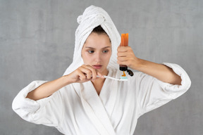 Woman in bathrobe squeezing toothpaste out of tube