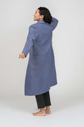 Rear view of a cheerful woman in coat