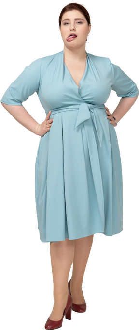 Vista frontale di una donna in abito blu in piedi con le mani sui fianchi e facendo smorfie