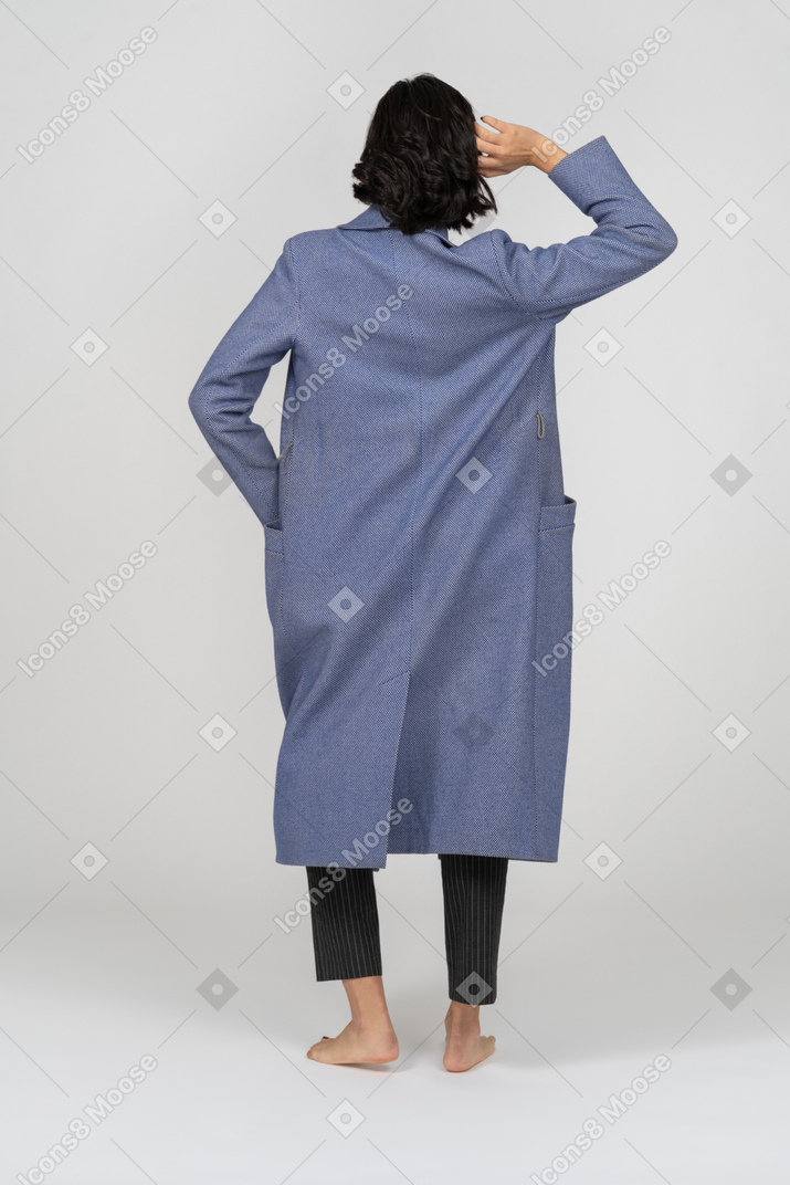 Vista trasera de una mujer con abrigo posando