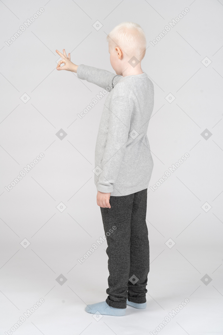 Side view of a little boy showing ok gesture