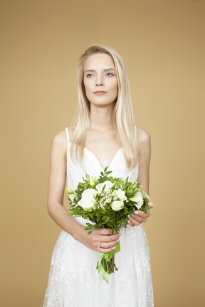 Belle jeune mariée tenant le bouquet de fleurs blanches