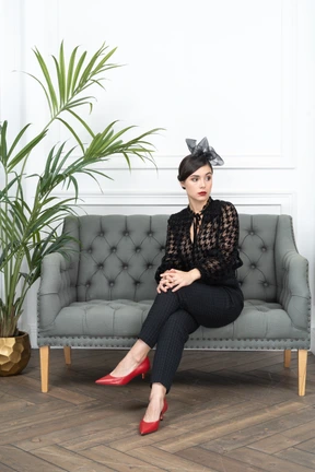 A woman sitting on top of a couch next to a potted plant