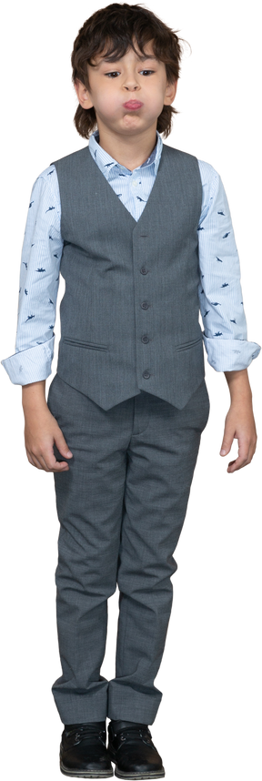 Vista frontal de um menino de terno cinza com as bochechas bufantes