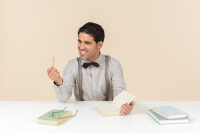 Feliz procurando estudante adulto sentado à mesa e ler um livro