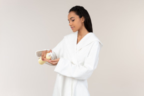 Black woman in white bathrobe going about her morning routine