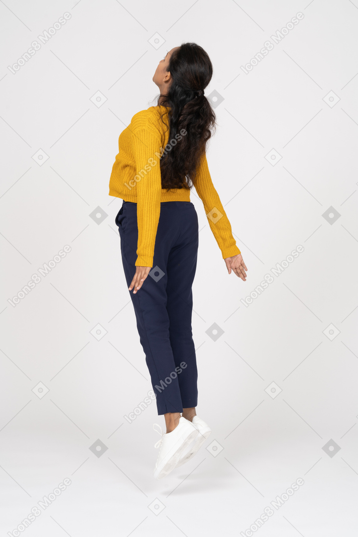 Retrovisor de uma garota com roupas casuais pulando com os braços estendidos