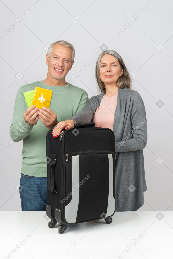 Middle aged couple holding suitcase and passports