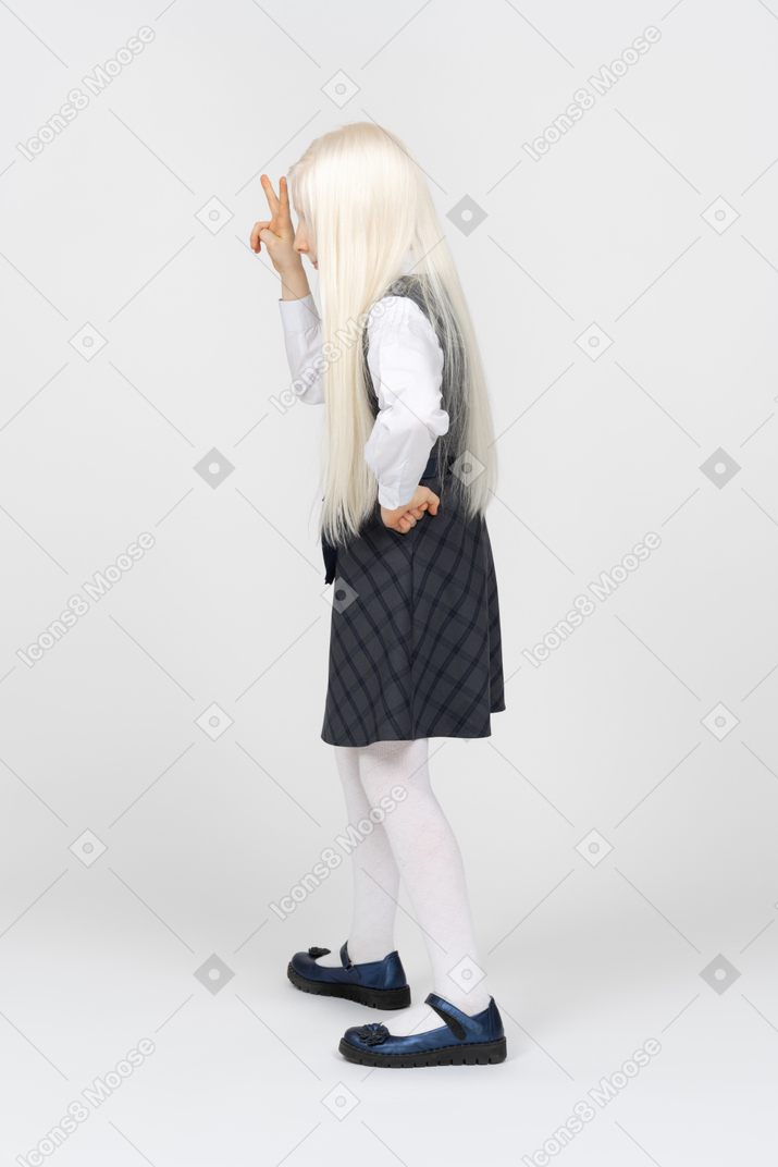 Side view of a schoolgirl making victory sign