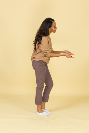 Side view of a dark-skinned smiling young female outstretching her hands