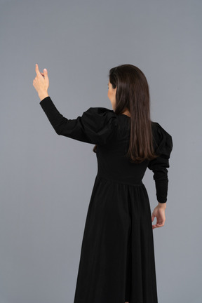 Back view of a young lady in a black dress raising her hand