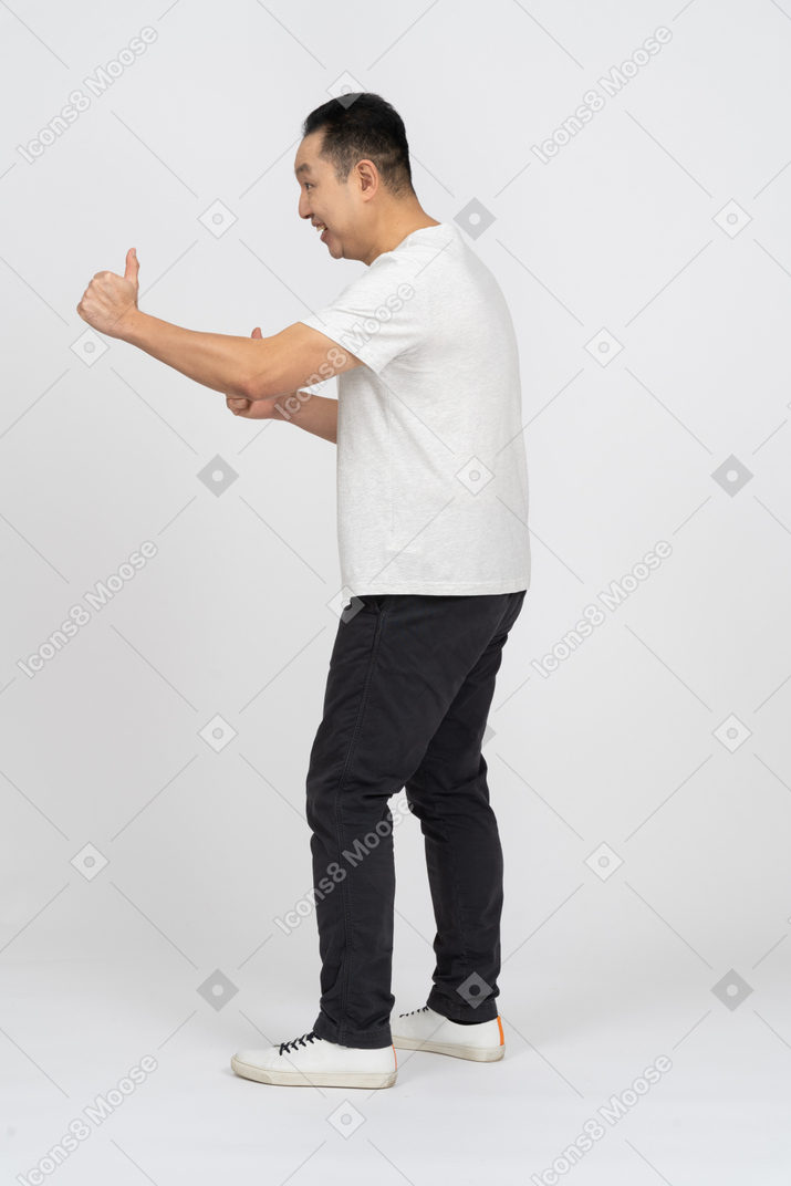 Vista lateral de un hombre feliz en ropa casual mostrando los pulgares para arriba