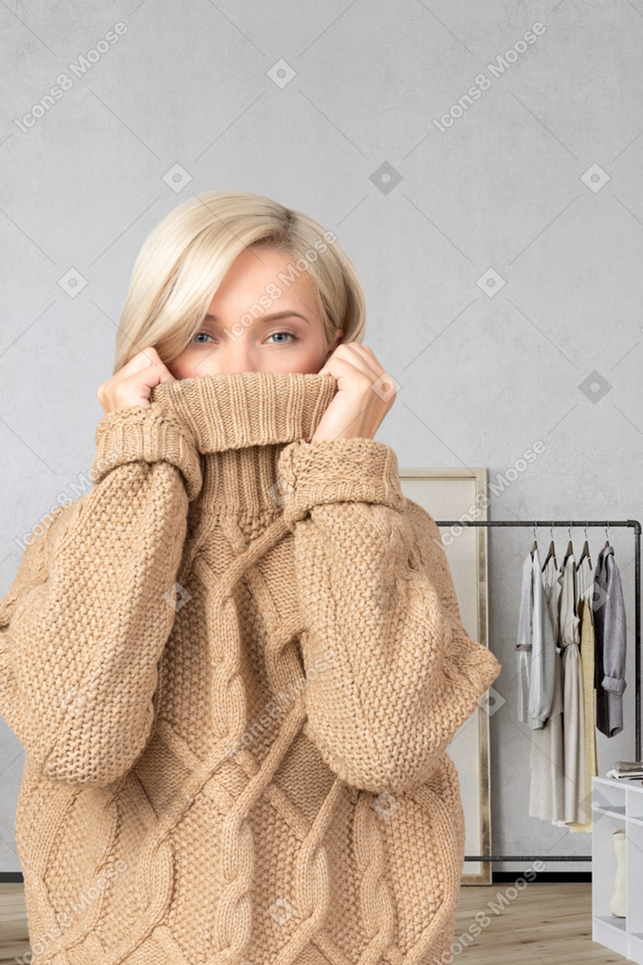 A woman pulling her sweater over her face