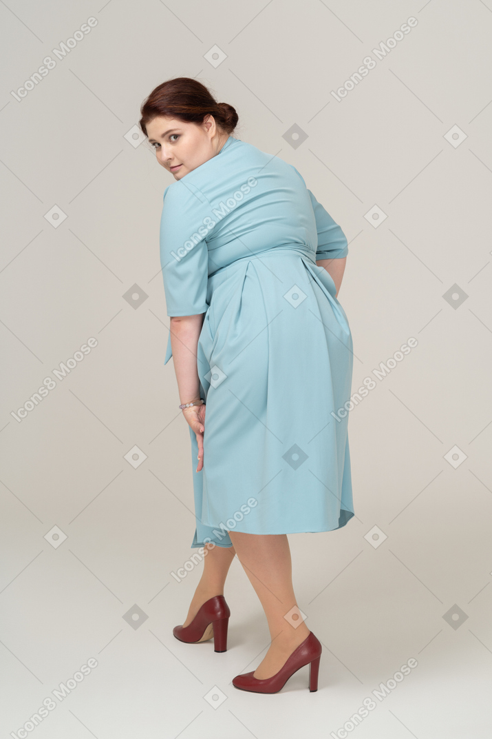 青いドレスのポーズをとって女性の背面図
