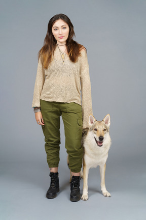 Pleine longueur d'un maître féminin debout près de son chien et regardant la caméra