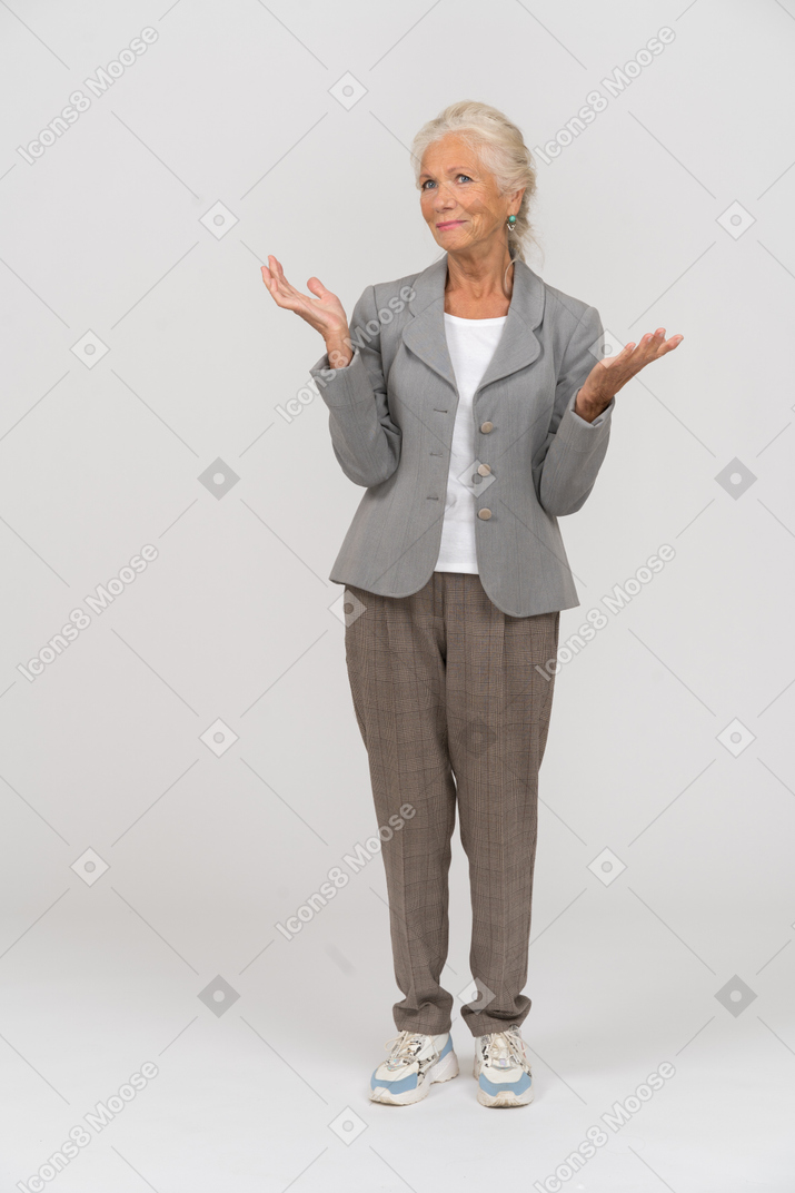 一位身着西装的老妇人举起双手站立的前视图
