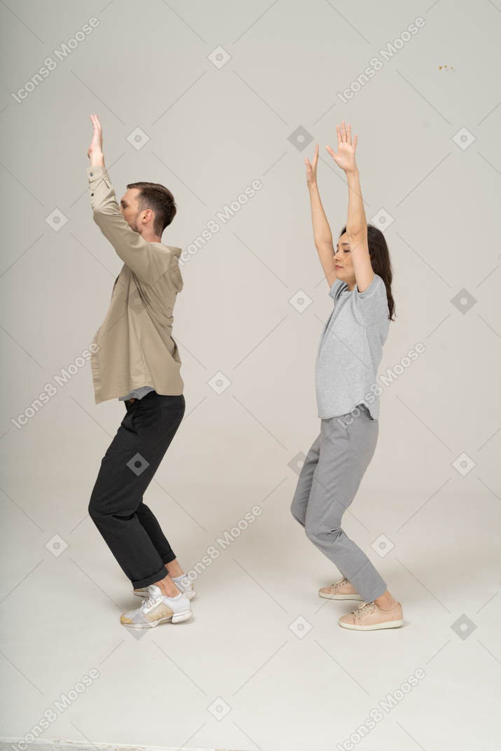 Side view of young man and woman with hands up