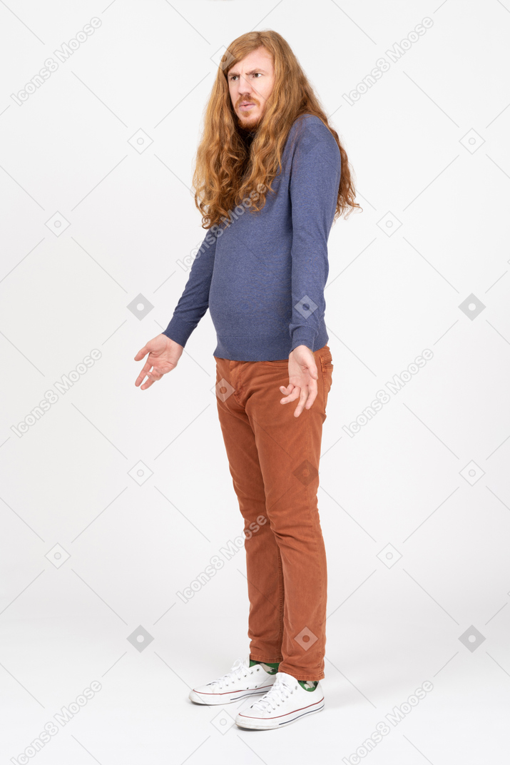 Side view of a confused young man standing with outstretched arms