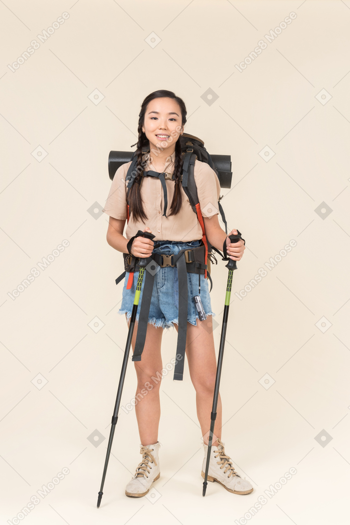 Joven excursionista asiática chica de pie con bastones de trekking en manos