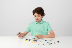 Boy in green polo shirt playing with construction set