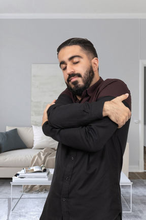 A man standing in a living room with his arms crossed