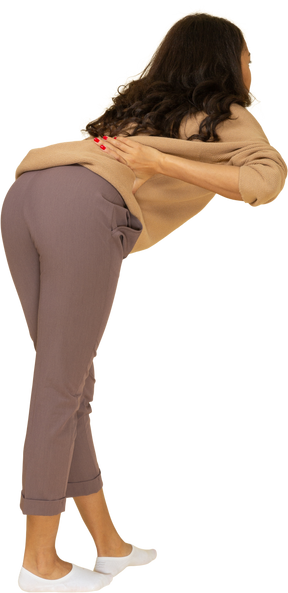 Vista posteriore di tre quarti di una giovane femmina dalla carnagione scura che si protende in avanti mentre mette le mani sui fianchi
