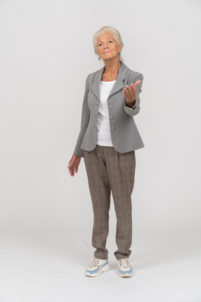 Vista frontal de una anciana en traje haciendo un gesto de bienvenida