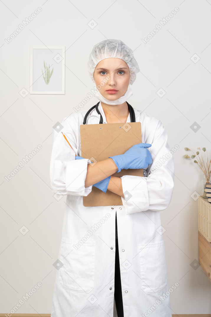 Vista frontal de uma jovem médica segurando um lápis e um tablet