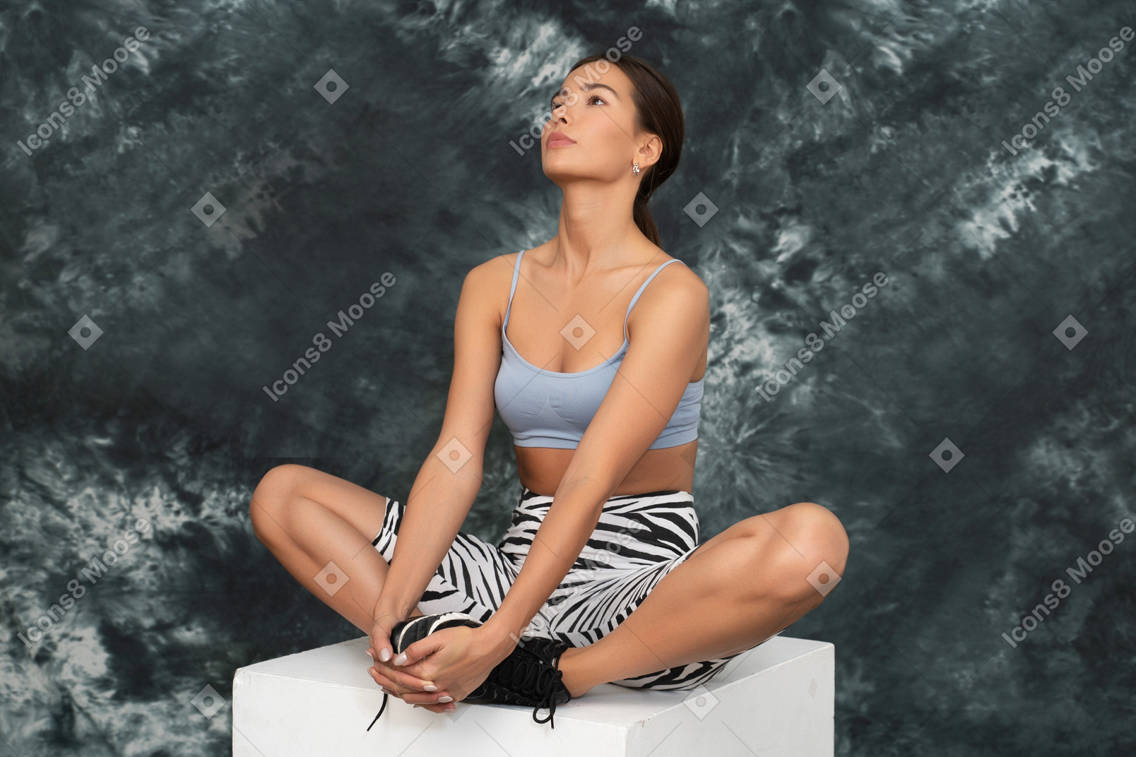 Atleta feminina olhando para cima e sentada em posição de lótus