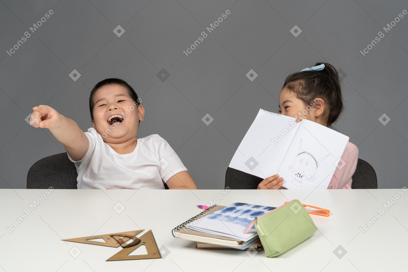Boy laughing and pointing his finger next to his sister