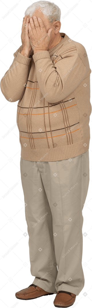 Vista frontal de un anciano con ropa informal que cubre la cara con las manos