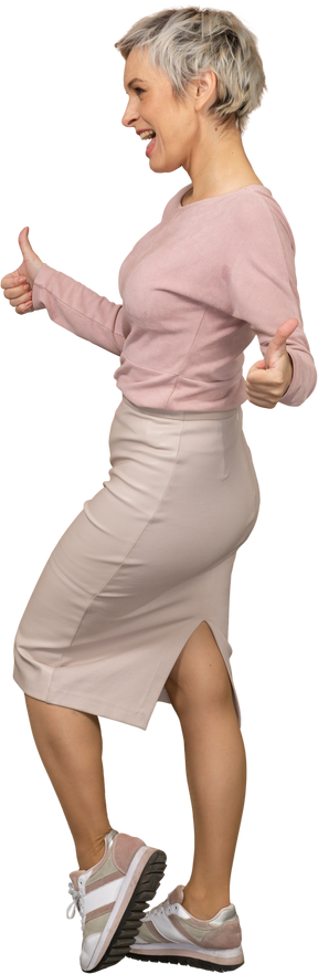 Side view of a happy woman in casual clothes showing thumbs up