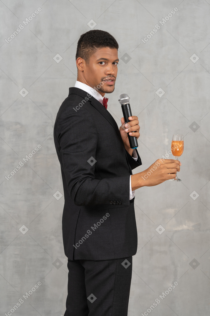 Young man with a mic and flute glass looking at camera