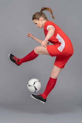 Eine sportliche junge frau, die mit ball springt