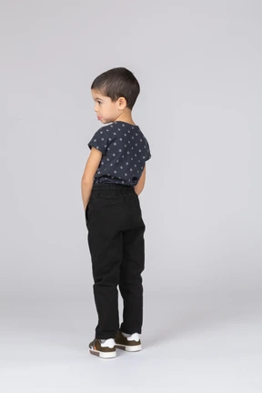 Side view of a cute boy in casual clothes making faces