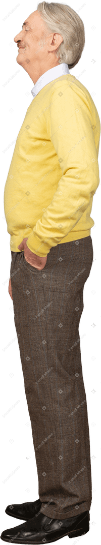 高兴的老人，穿着黄色套衫，将手放在口袋里的侧视图