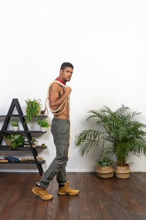 Side view of muscular young man walking and looking at camera