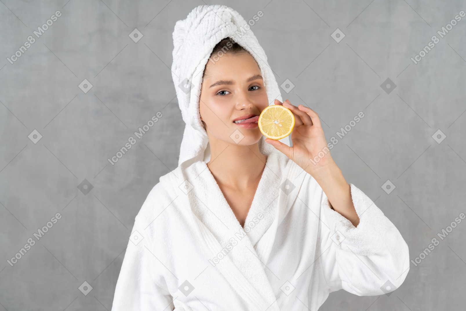Веселая женщина в халате облизывает лимон