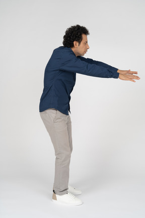 Vista lateral de um homem com roupas casuais posando com os braços estendidos