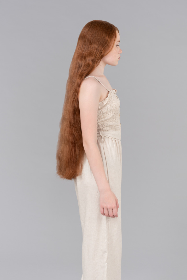 Teenage girl with long red hair standing in profile