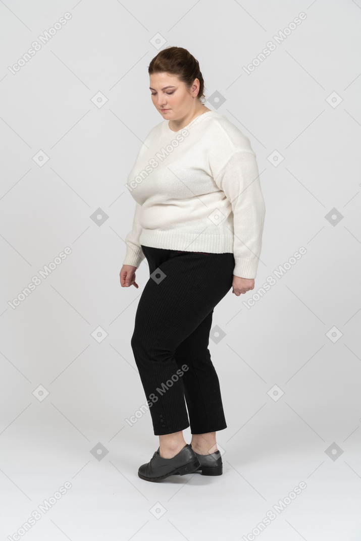 Donna grassoccia in maglione bianco in piedi con le mani dietro la testa