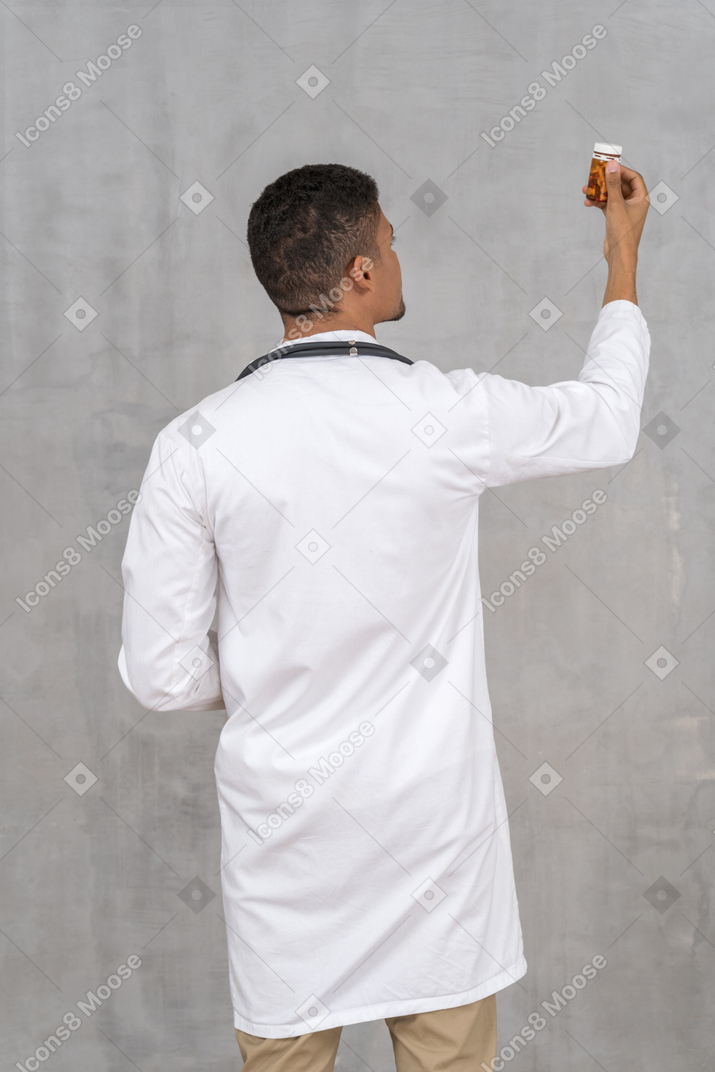 Male doctor looking at bottle of pills