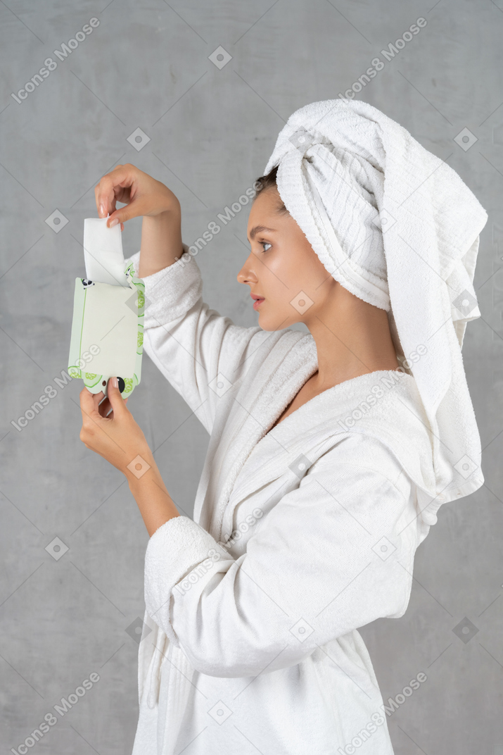 Side view of a woman taking a sheet mask out of pack