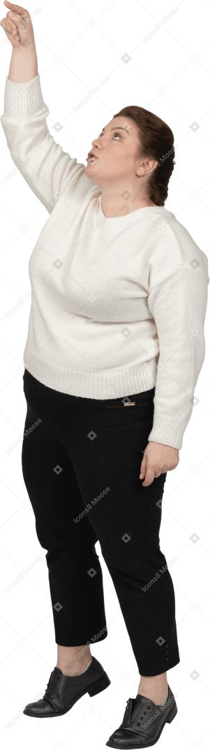 Vista lateral de uma mulher plus size com roupas casuais apontando para cima