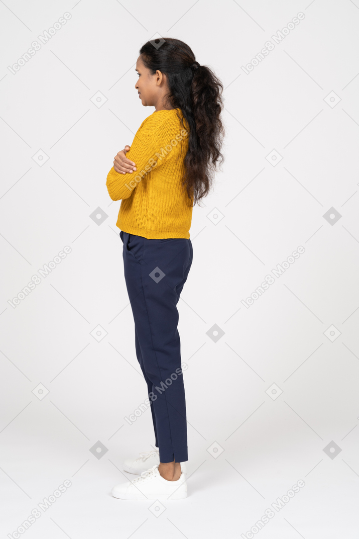 Vista laterale di una ragazza in abiti casual in piedi con le braccia incrociate